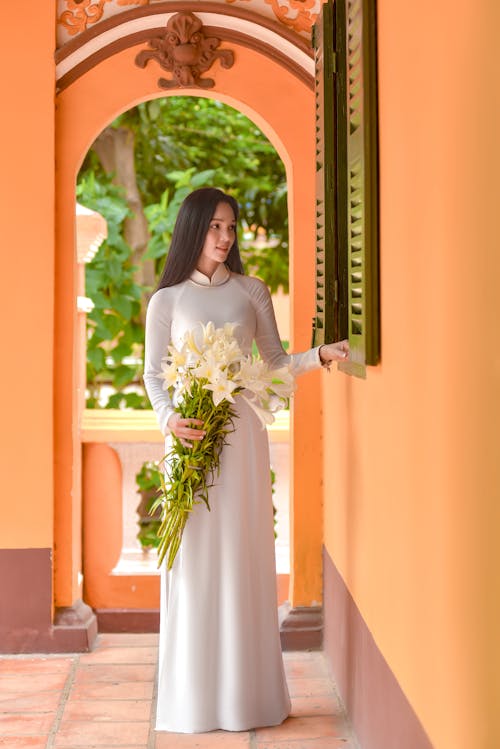 Free Woman in White Dress Holding Flowers Stock Photo