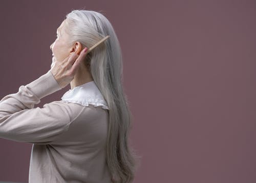An Elderly Woman Combing Her Hair