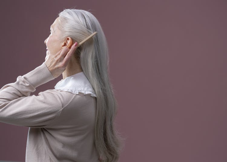 An Elderly Woman Combing Her Hair