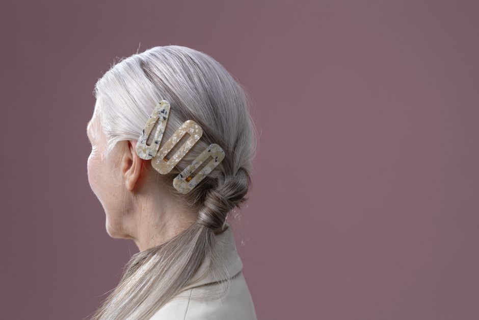 Close-up portrait of a senior woman with a stylish hair barrette in a studio setting.
