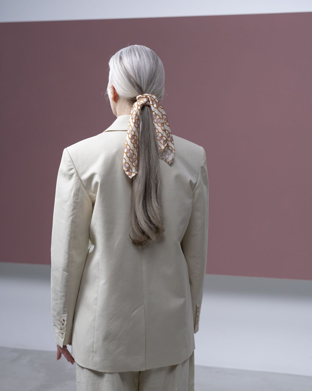 bandana hairstyles 2026 back view woman in beige suit with scarf tied on hair editorial