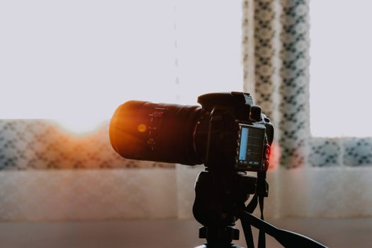 A DSLR camera set up on a tripod captures sunlight streaming through windows indoors.