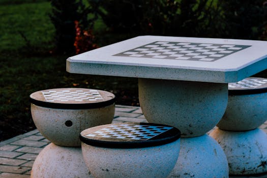 Outdoor concrete table and round stools with checkerboard design, perfect for chess or checkers.