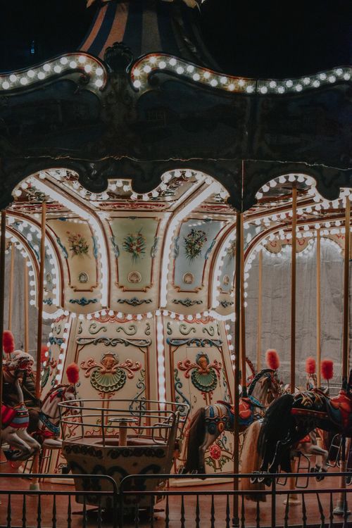 Free Enchanting lit carousel ride with vintage charm at a nighttime fairground setting. Stock Photo