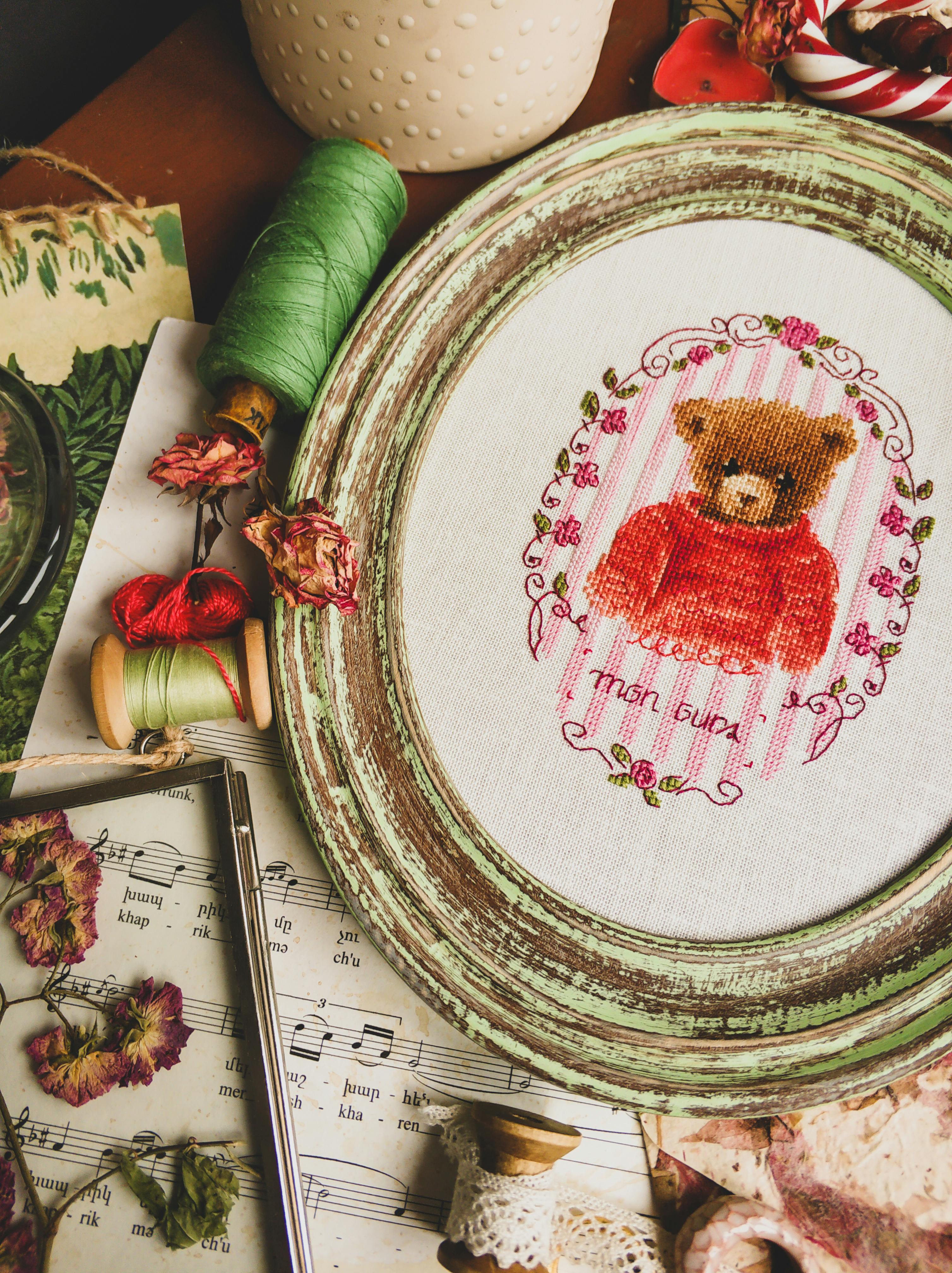 Cross stitch in frame placed near threads · Free Stock Photo