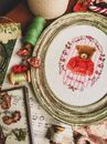 From above of handmade embroidery in frame placed near skeins of threads on sheet with notes