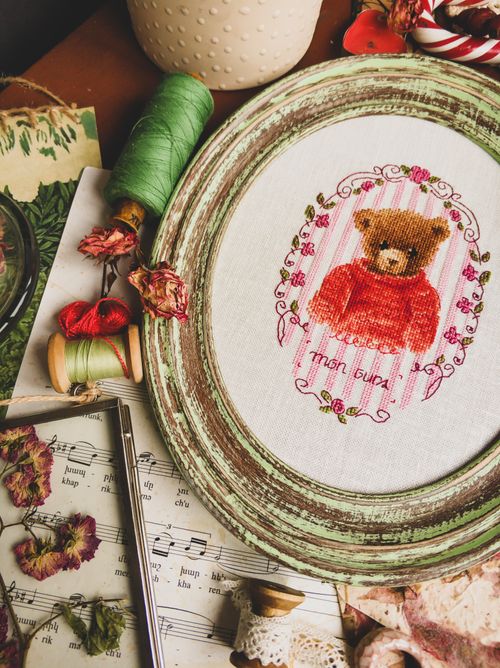 Free From above of handmade embroidery in frame placed near skeins of threads on sheet with notes Stock Photo