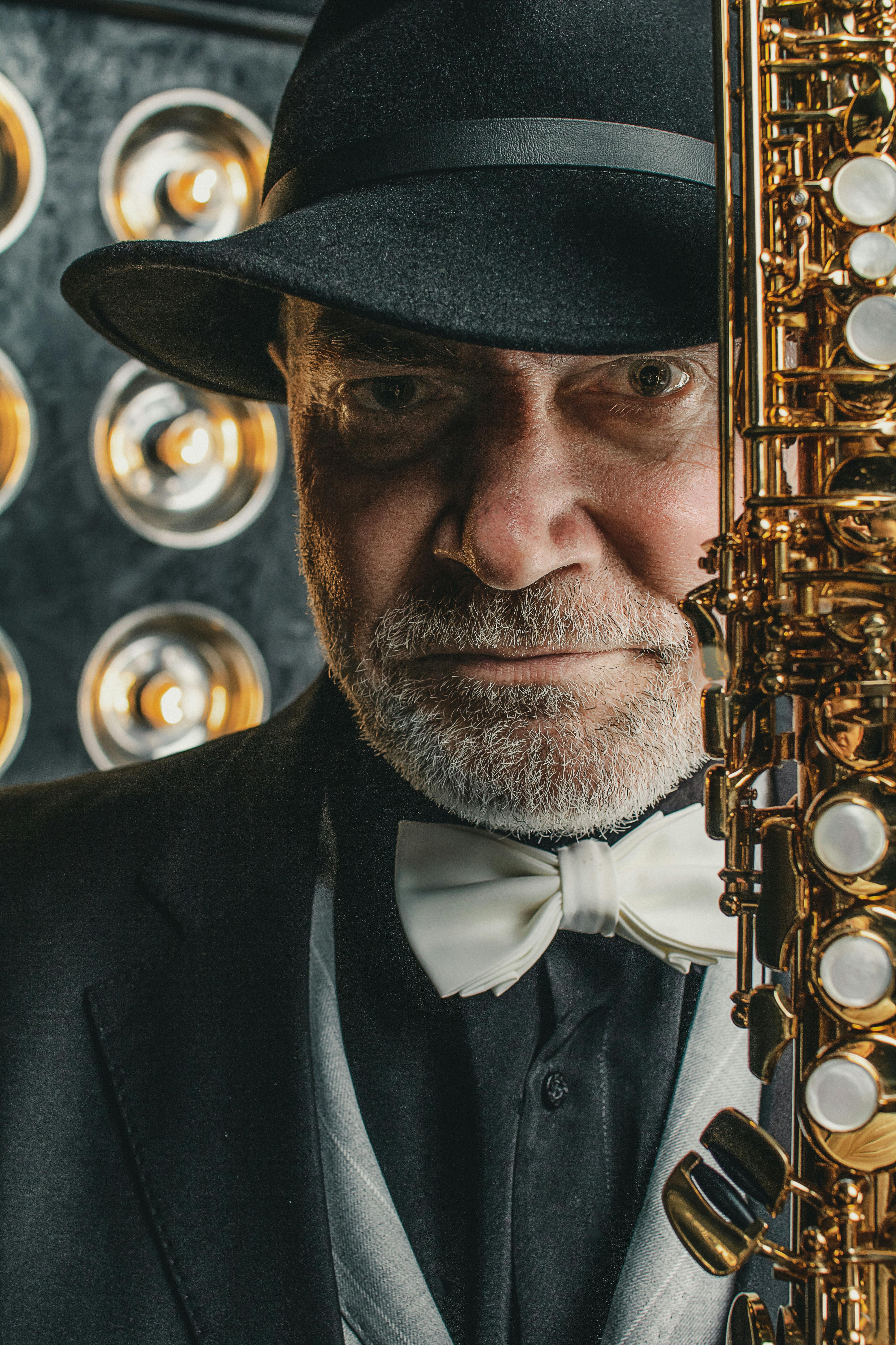 Portrait of a senior jazz musician in a suit and hat holding a saxophone, showcasing classic musical elegance.