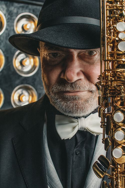 Free Portrait of a senior jazz musician in a suit and hat holding a saxophone, showcasing classic musical elegance. Stock Photo