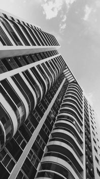 A striking black and white photo of a modern skyscraper with curved balconies, captured in an upward perspective.