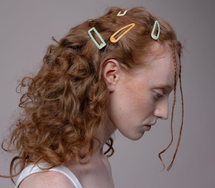 Close-up profile of a redheaded woman with stylish hair clips and curly hair.