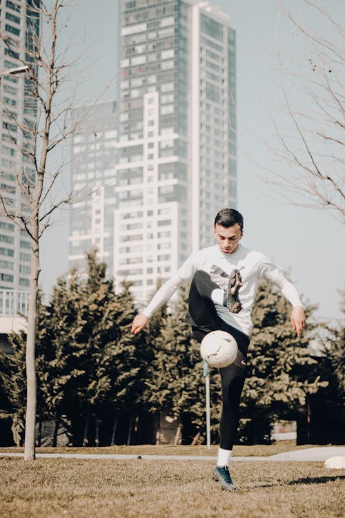 Man in White Long Sleeve Shirt and Black Pants Playing Soccer