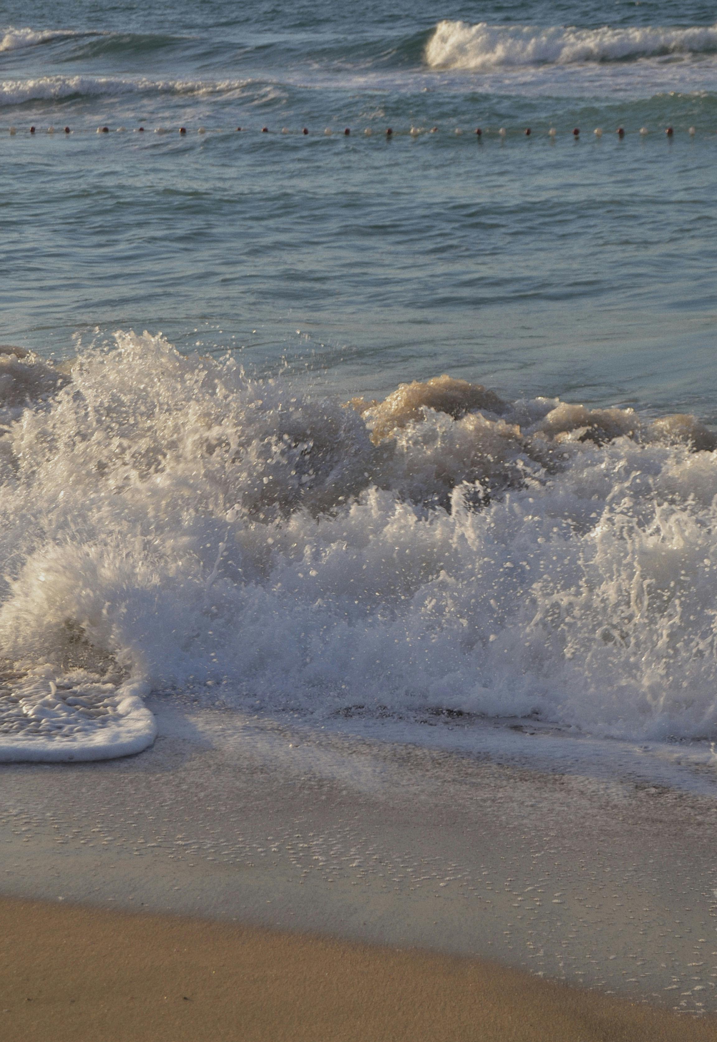 Capture of dynamic waves crashing onto a Turkish beach with clear blue sea.