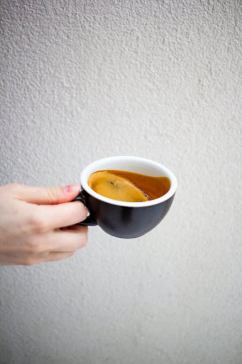 Crop unrecognizable person demonstrating cup of aromatic espresso