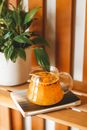 From above of glass jug with sweet morse placed on wooden table near verdant potted plant