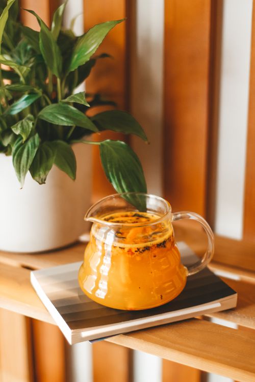 Free From above of glass jug with sweet morse placed on wooden table near verdant potted plant Stock Photo