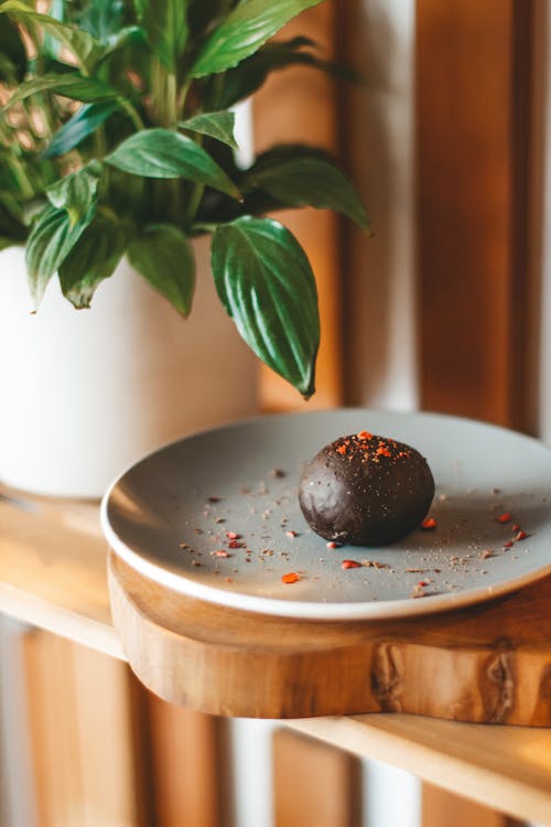 Chocolate potato cake placed on ceramic plate on timber table near potted plant in kitchen