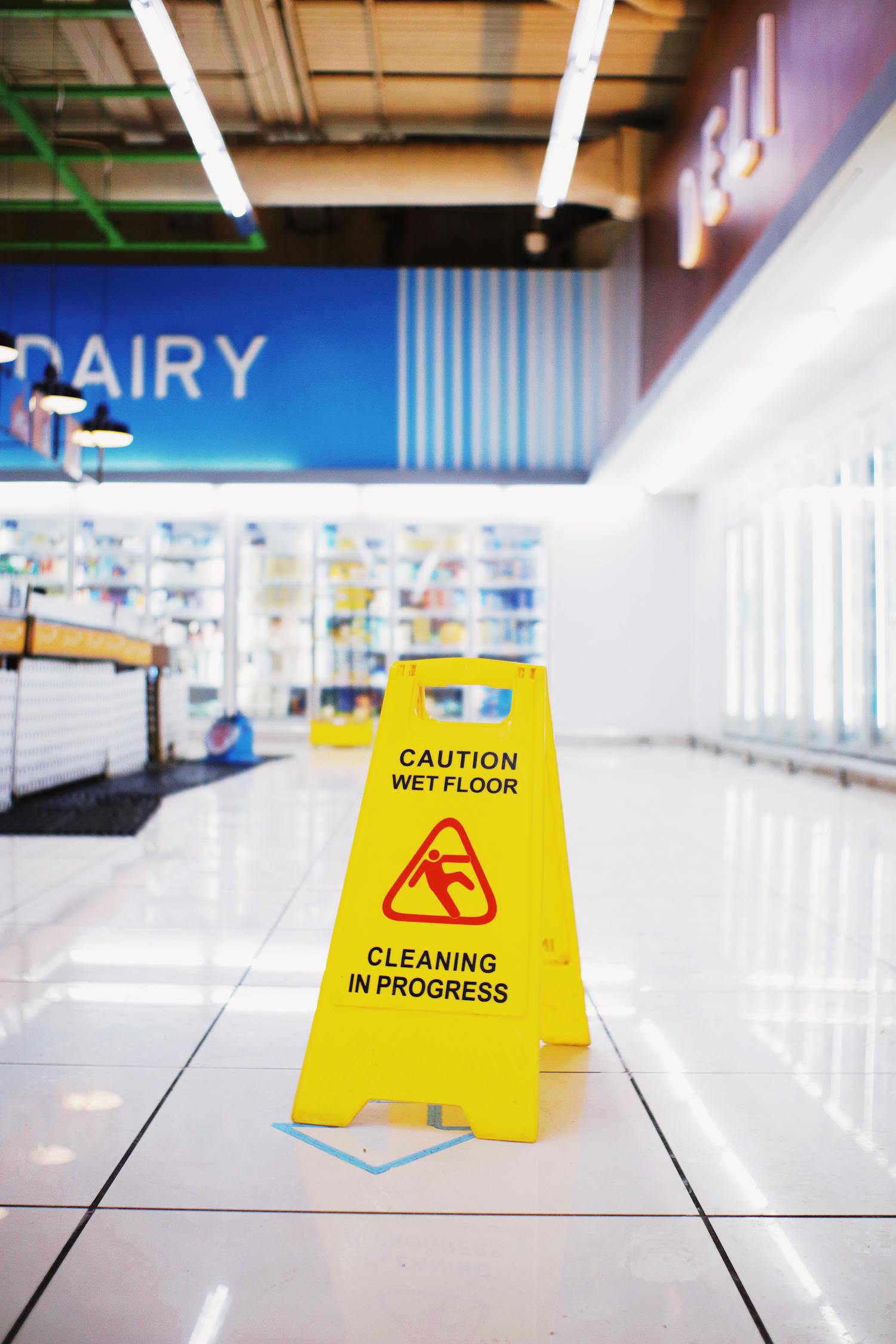 Yellow plastic warning sing with inscription Wet floor placed in empty store in modern mall