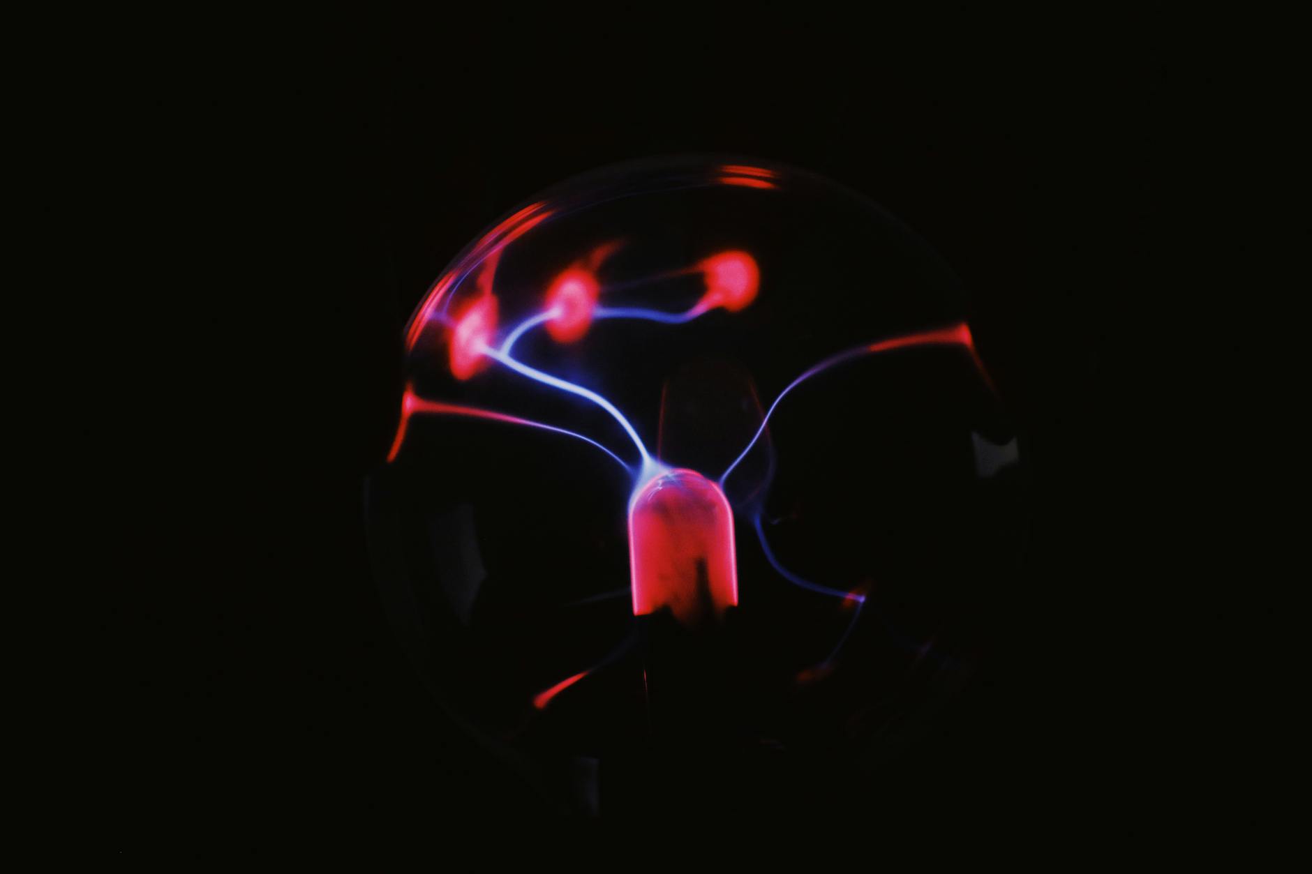 Bright plasma ball with red lights in darkness