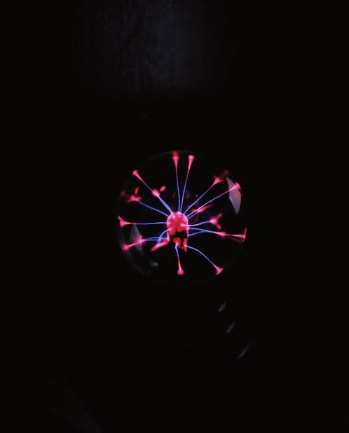Round magical plasma ball with colorful neon lights placed room against dark background