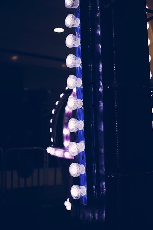 Bright glowing lights placed on colorful constructions in amusement park in evening time