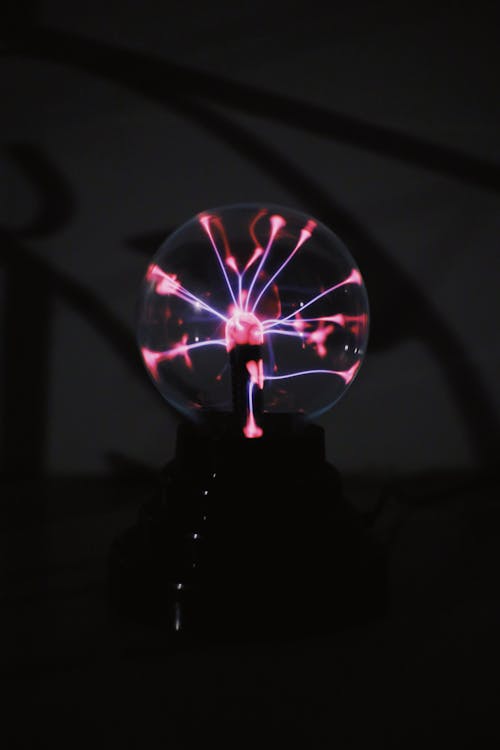 Shiny plasma ball with neon lights against dark background