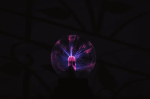 From below of glowing plasma ball with neon light placed in dark room