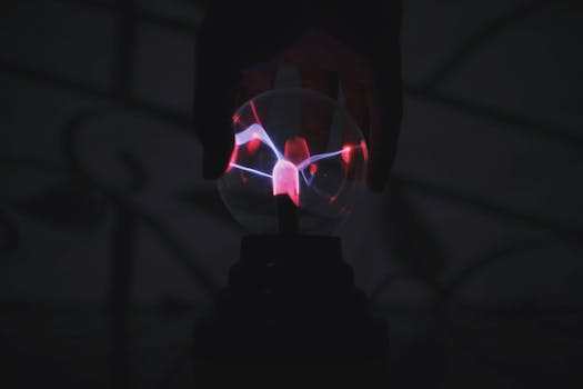 Close-up of a glowing plasma ball with a hand casting a shadow, creating a mystical atmosphere.