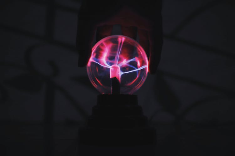 Person Touching Plasma Ball In Dark Room