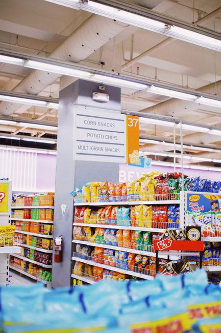 Shelves with assorted colorful corn snacks and potato chips placed in modern supermarket