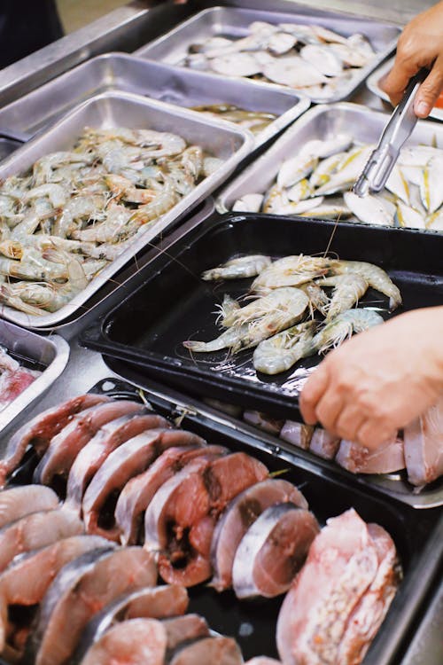 Free From above of crop anonymous seller putting fresh prawns in plastic container in local market Stock Photo