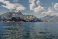 在明亮的天空下，科莫湖景色令人惊叹，四周环绕着郁郁葱葱的山脉和平静的海水