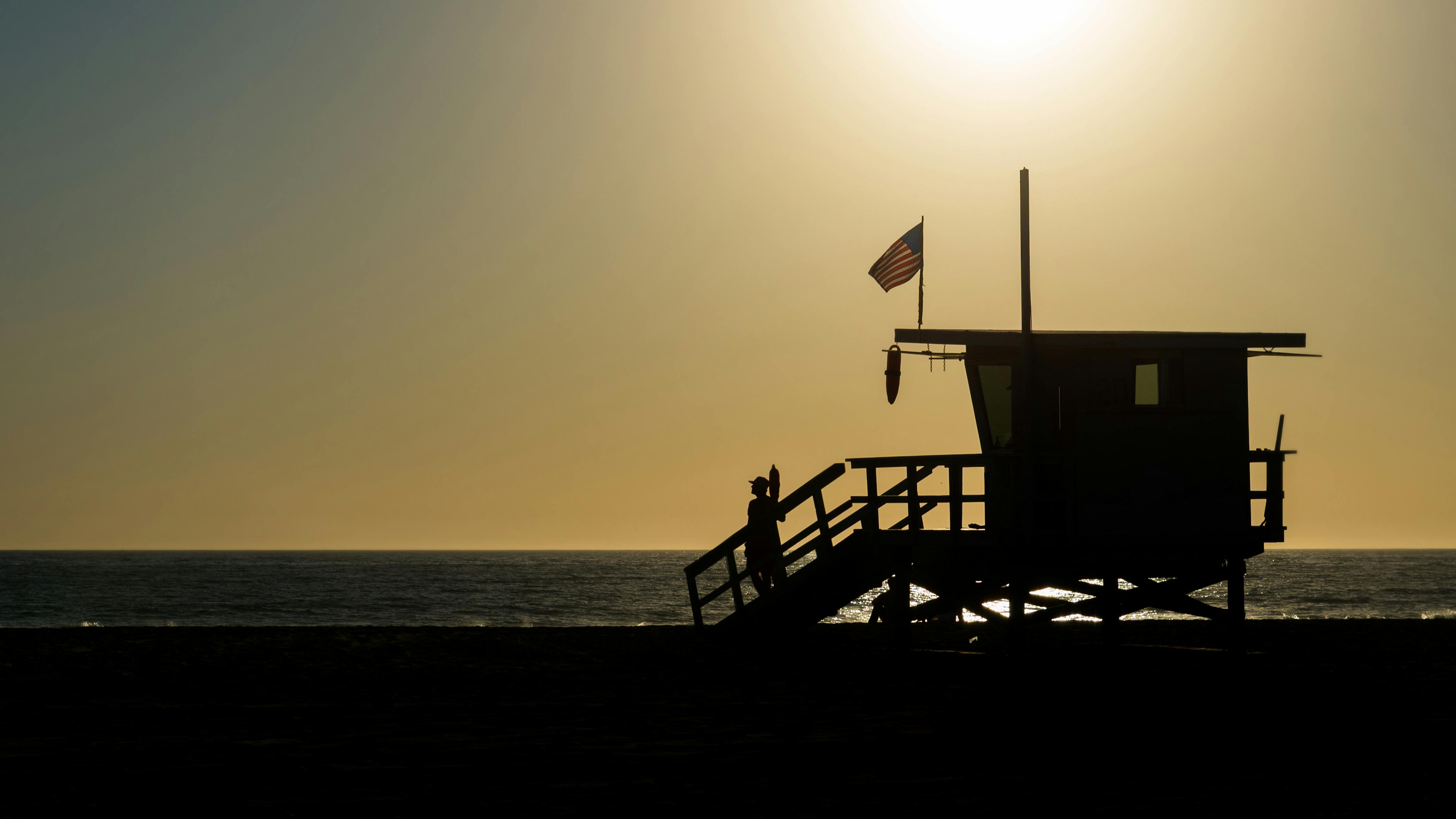 silhouette of life guard house near ocean during sunset