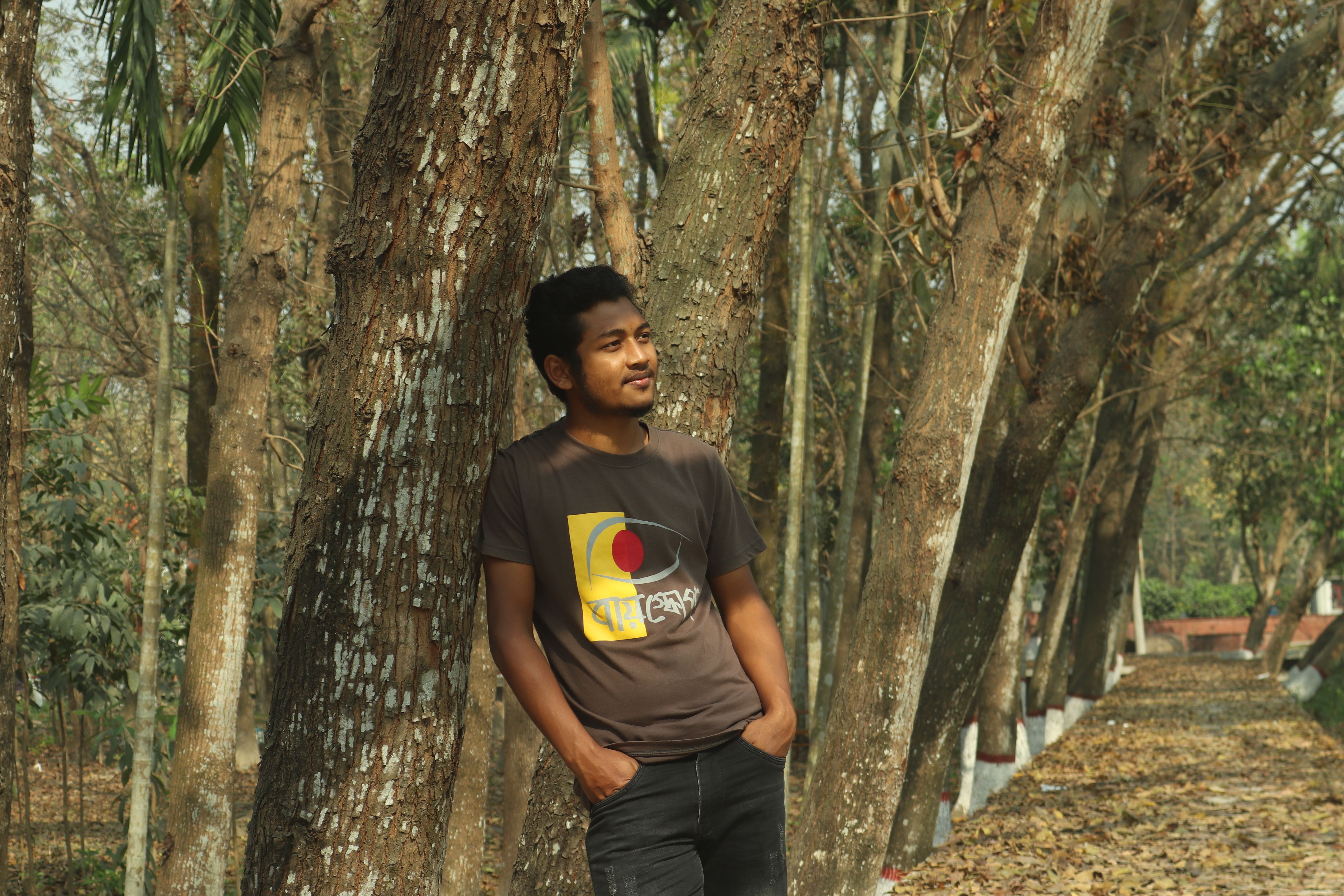 Portrait of a young man smiling in a serene forest setting in Khulna, Bangladesh.