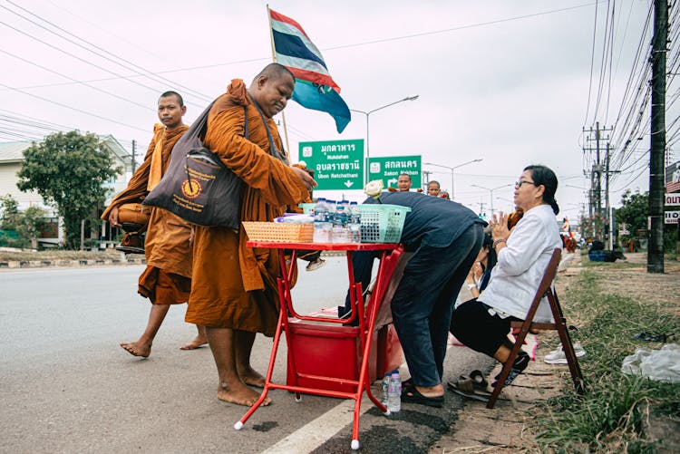 Monks On A Pilgrimage Buying Refreshments From A Stall