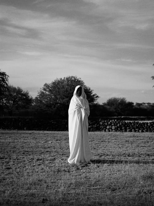 Free Grayscale Photo of Person Covering With Blanket while Standing on the Grass Stock Photo