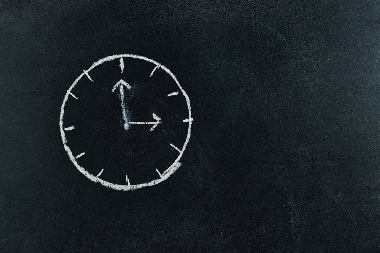 chalk drawn clock on a blackboard symbolizing time and education conce