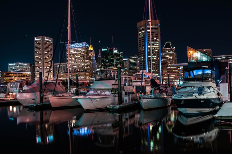 Baltimore skyline lit at night above yachts docked in the Inner Harbor marina