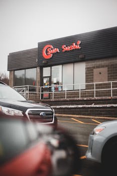 Modern cars parked near building of cafe with Asian food under cloudy sky in daytime