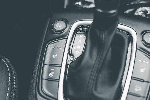 Close-up of a gear shift lever in a modern car, captured in black and white.