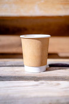 Single-use eco-friendly coffee cup on a rustic wooden table.