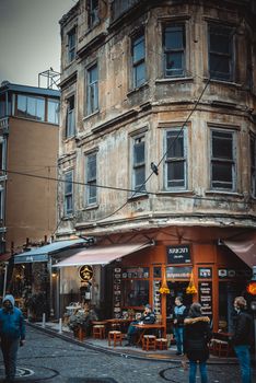 Vintage building on a busy city street corner with pedestrians and a cozy café vibe.