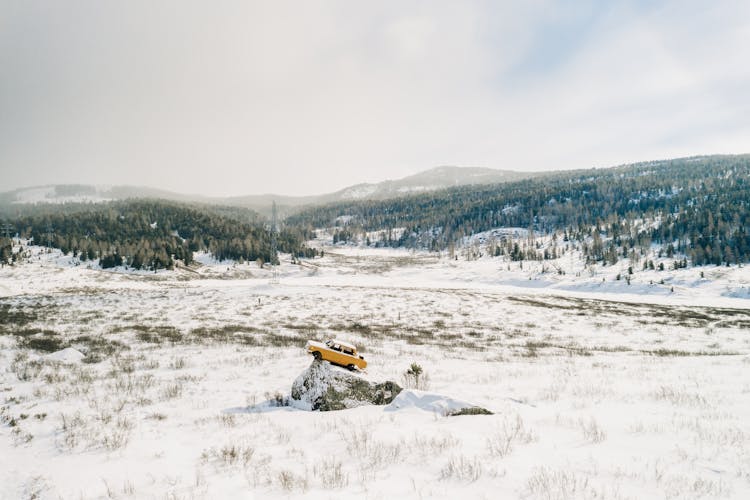 Yellow Car On Snow Covered Rock