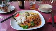 在舒适的餐厅享用美味的亚洲猪肉菜、蔬菜和米饭，配上冰镇啤酒