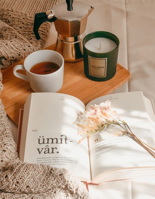 A serene still life featuring coffee, a candle, and a book on a cozy setting, perfect for relaxation.