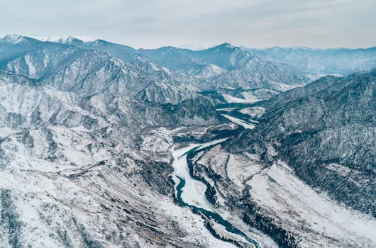 A breathtaking aerial view of snow-covered mountains and rivers during winter.