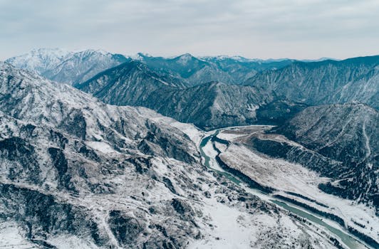 Stunning aerial photograph showcasing a snow-covered mountain range with winding river.