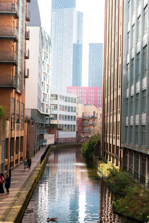 Free Scenic view of a canal in Manchester flanked by modern high-rise buildings and historic architecture. Stock Photo