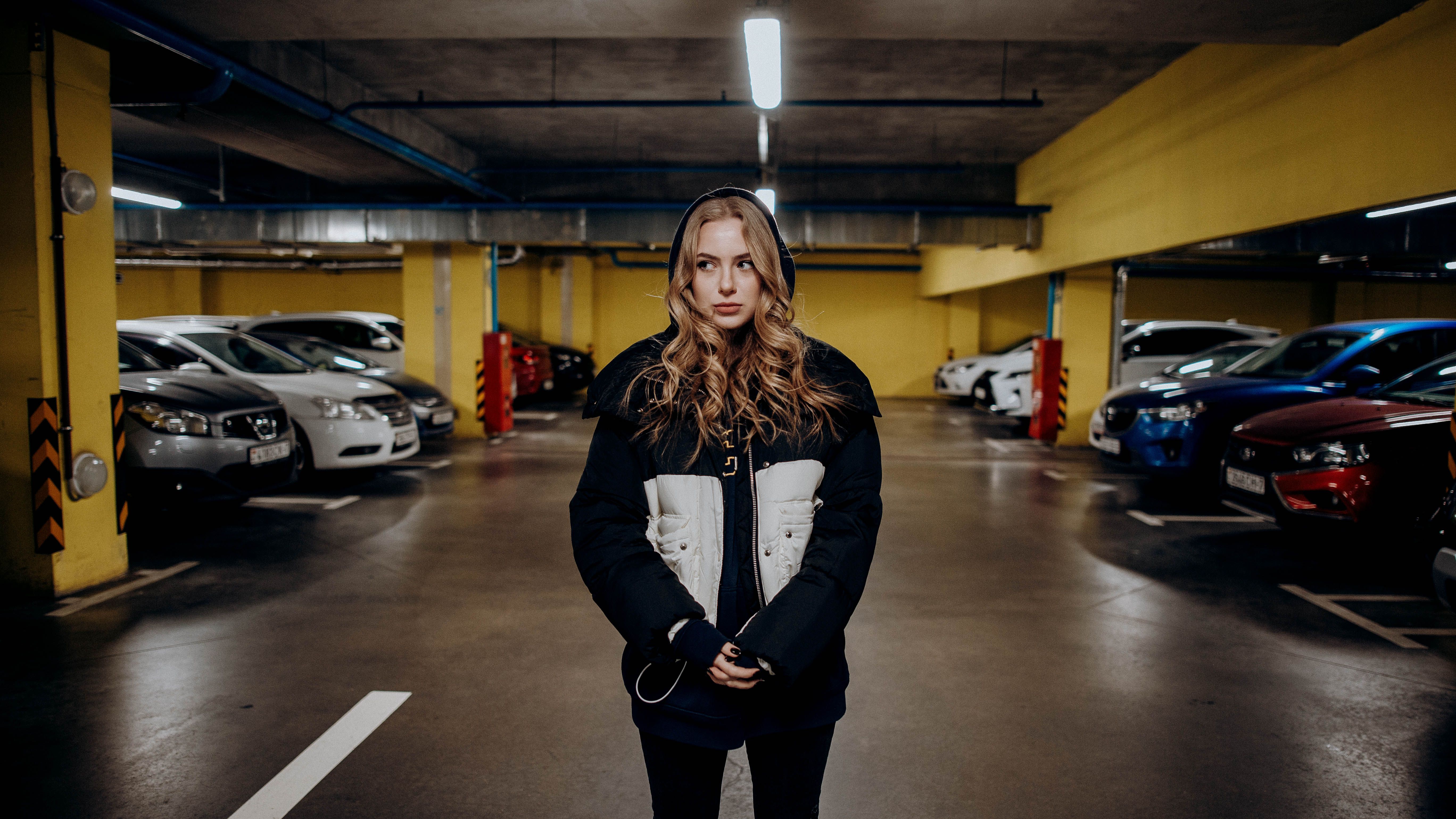 Woman in Black Jacket Standing on a Parking Lot · Free Stock Photo