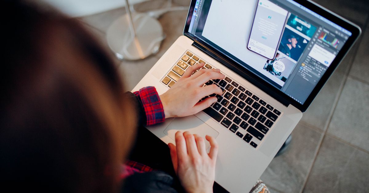 Close-up of a person working on a laptop with graphic design software.